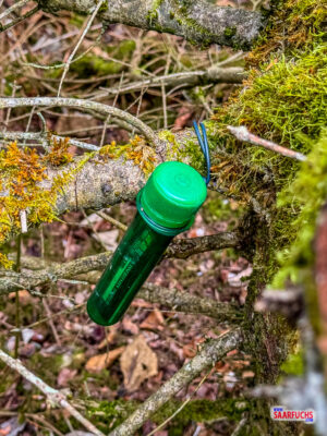 Kleiner Geocaching-Beh&auml;lter aus Kunststoff versteckt in einer typischen Nische am Wegesrand