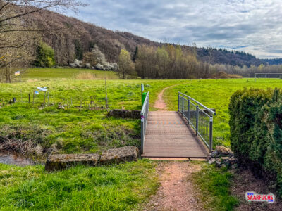 Kleine Br&uuml;cke &uuml;ber den Bach Leuk mit Uferbewuchs in der Ortslage von Trassem