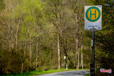 Eine Bushaltestelle im Gr&uuml;nen mit einem l&auml;ndlichen Fahrplanaushang