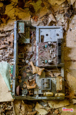Auf dem Boden liegende, besch&auml;digte Elektronikbauteile und Kabelreste in einem verlassenen Raum