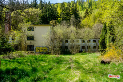 R&uuml;ckblick auf die graue, verwitterte Fassade des ehemaligen Wald- und Jugendhotels beim Verlassen des Gel&auml;ndes