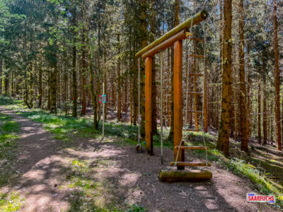 Eine h&ouml;lzerne Kletterstation als Teil des Fitnesspfads inmitten von B&auml;umen