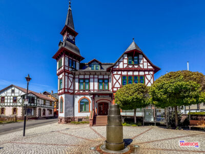 Das historische Rathaus von Steinbach-Hallenberg mit seiner hellen Fassade und dunklen Holzbalken unter blauem Himmel