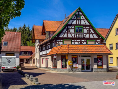 Eine Reihe von restaurierten Fachwerkh&auml;usern mit detailreichen Holzverzierungen entlang der Hauptstra&szlig;e