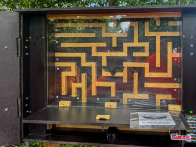 Blick in das Innere einer Geocaching-Kiste mit einem eingebauten Holzlabyrinth