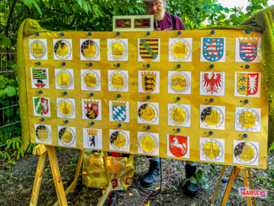 Eine gro&szlig;e elektronische Spieltafel im Jugendzentrum mit Abbildungen von M&uuml;nzen und historischen Wappen