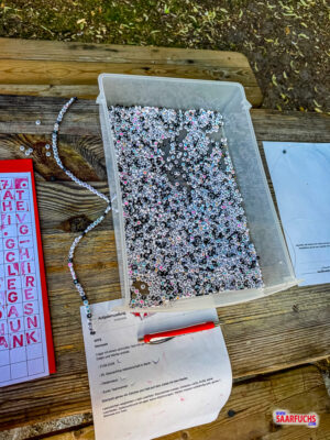 Nahaufnahme von kleinen, bunten Plastikteilen mit Zahlenbeschriftung, die auf eine Schnur gef&auml;delt werden