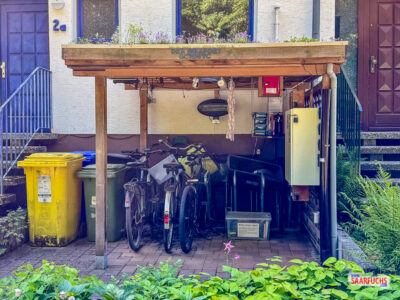 Au&szlig;enansicht einer h&ouml;lzernen Fahrrad&uuml;berdachung im Vorgarten eines Reihenhauses in Lang-G&ouml;ns