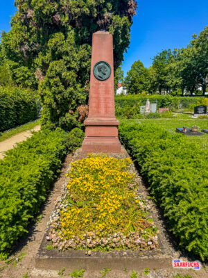 Das steinerne Grabmal von Philipp Reis auf dem Friedhof in Friedrichsdorf im Schatten von B&auml;umen]