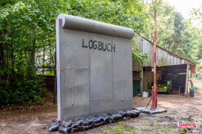 Eine große, hölzerne Mauer auf dem Eventgelände, die als überdimensionales Logbuch für das Mega-Event dient