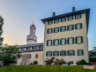 Perspektive aus dem Schlossgarten auf die historischen Seitengebäude und den aufragenden Weißen Turm