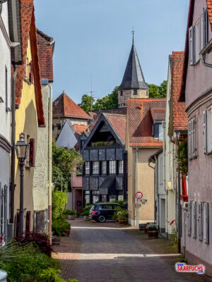 Blick auf den runden, mittelalterlichen Hexenturm aus Stein an einer Straßenkreuzung der Altstadt