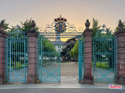 Das große Schmiedeeisentor mit dem historischen Familienwappen über dem Schlosseingang