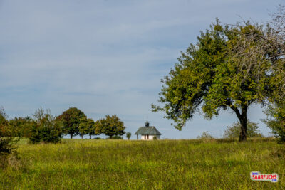 Blick &uuml;ber die Felder auf die silhouettenhaft in der Ferne stehende Kapelle