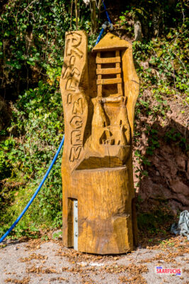 Kunstvoll geschnitzte Holzfigur am Beginn des seilgesicherten Hangabstiegs