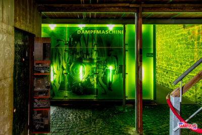 Farbige Lichtinstallation und rustikaler Gang im Inneren des historischen Trafohauses