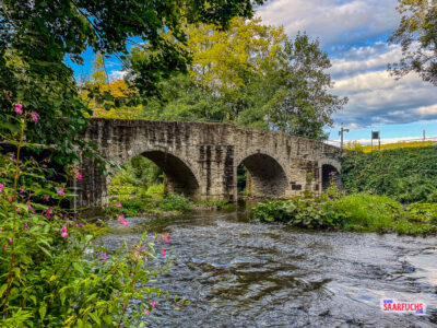 Blick von der Seite auf die historische Nisterbrücke als Zugang zur Abtei Marienstatt