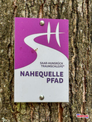 Nahaufnahme eines Schildes der Traumschleife Nahequelle-Pfad mit der charakteristischen Markierung