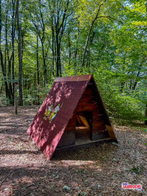 Kleine hölzerne Hütte am Rande eines bewaldeten Wanderwegs