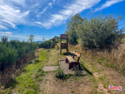 Rastplatz mit Holzbänken, Spiel-Stelzenhaus und einer Schaukel am Wiesenrand