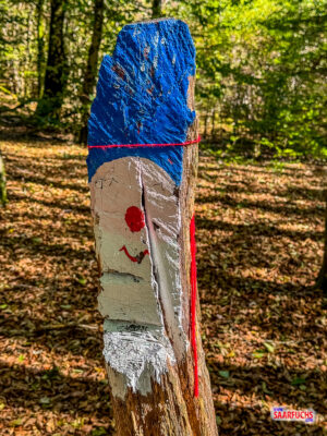 Bunt bemalte kleine Holzfiguren in Koboldform am Waldweg