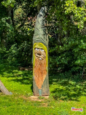 Detailreiche Holzskulptur neben dem Startportal des Wanderwegs