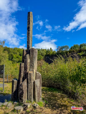 Ein aus Basaltsteinen errichtetes Denkmal an einem Aussichtspunkt über dem See