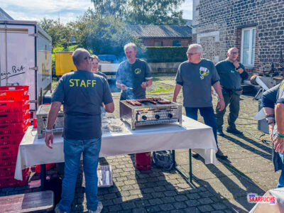 Dampfender Holzkohlegrill mit bratenden Würsten auf dem Außengelände des Events