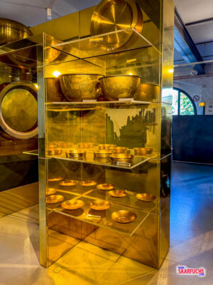 Ausstellungsstücke aus Messing wie historische Pfannen und Schüsseln im Museumskeller