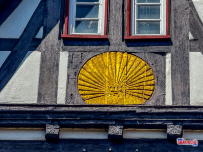 Detailansicht des Fachwerkgiebels mit der verzierten goldenen Fächerrosette